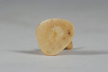 A miniature ancient Inuit game piece carved from walrus ivory